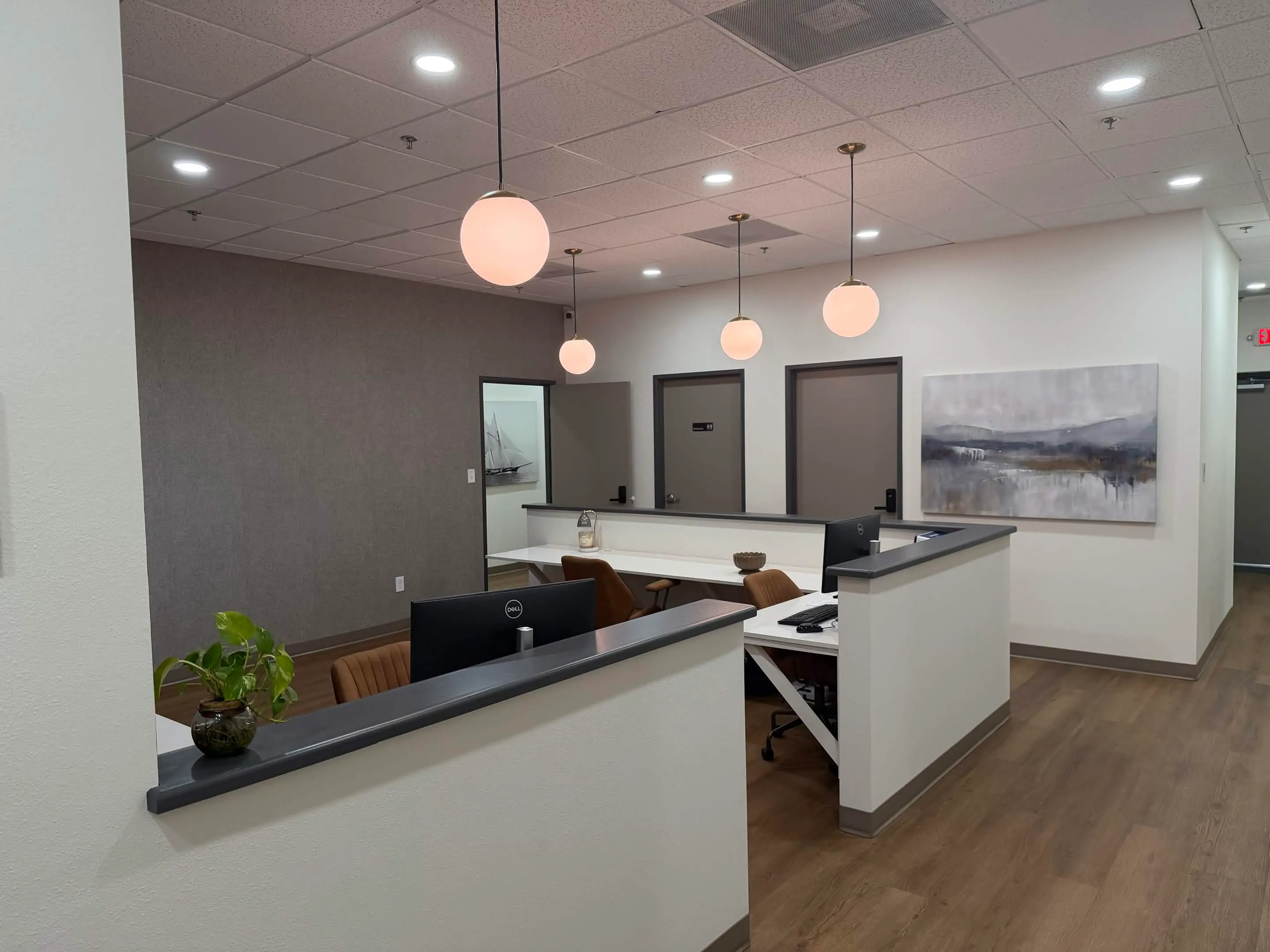 Central care team workspace with computers, warm pendant lighting, and nearby patient rooms